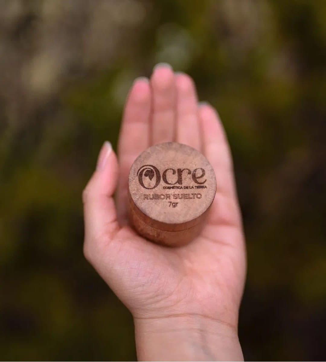 Une main tient un pot en bois gravé Ocre, Cosmética de la Tierra, le premier nom du projet en Colombie