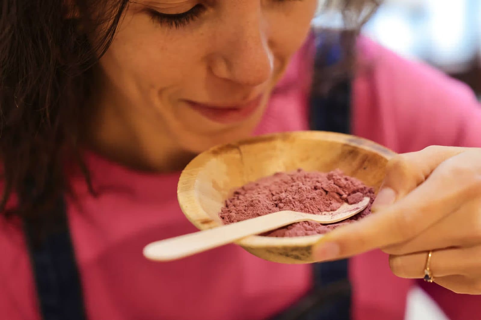 Una participante huele un polvo rosa en un cuenco de madera